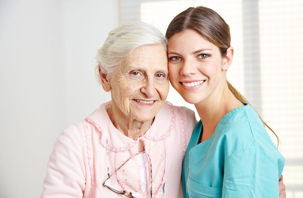 A nurse and a senior woman smiling and embracing.