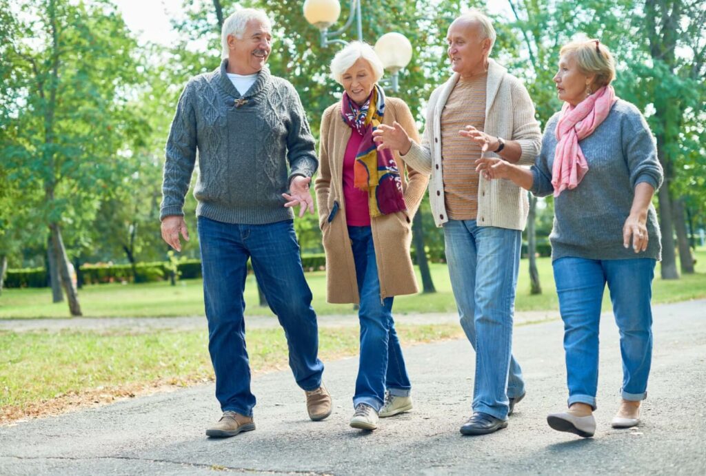 A group of seniors walking together in the garden area of their new assisted living community