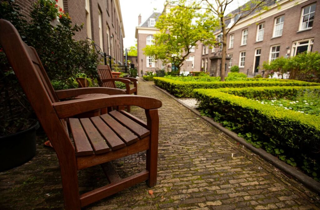 A villa-style assisted living community outdoor common area with wooden chairs and lush greenery.