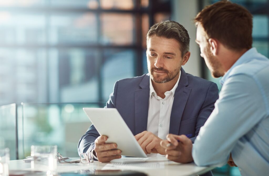 A business team collaborates around a tablet in an office, using technology to plan the opening of a senior living community.