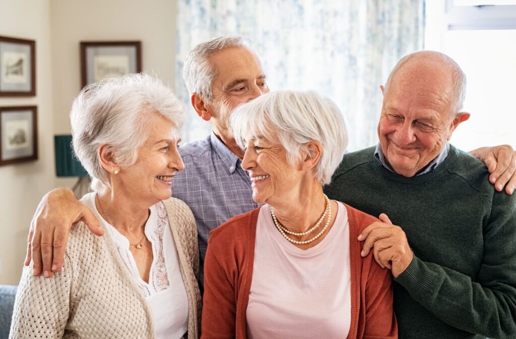 a group of seniors in a nursing home stand together and smile at one another